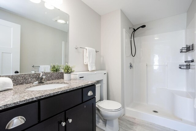 full bath featuring wood finished floors, vanity, toilet, and a shower