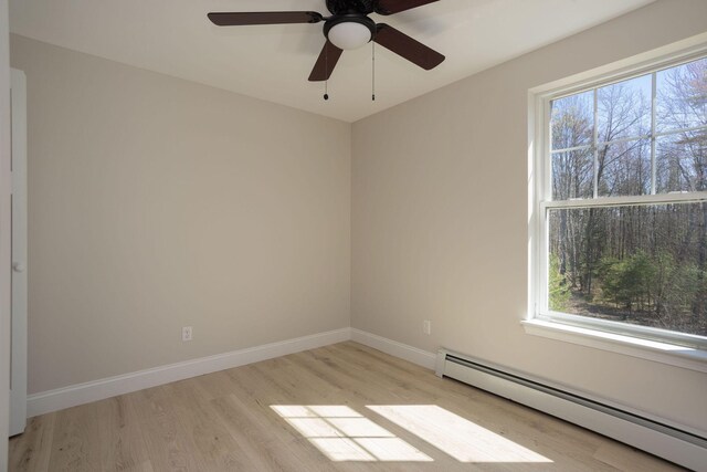 spare room with a baseboard radiator, a wealth of natural light, wood finished floors, and ceiling fan