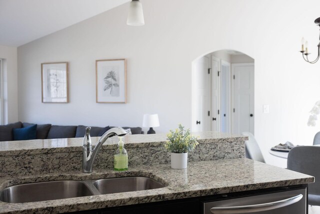 kitchen with light stone countertops, arched walkways, open floor plan, and a sink