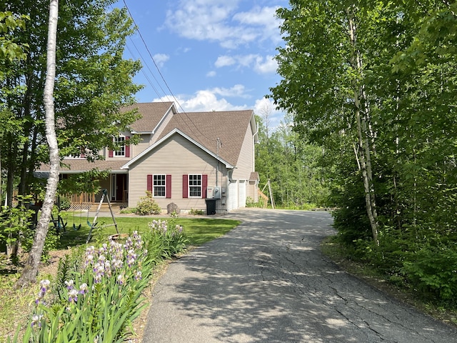 38 Dunston Dr, Glenburn, ME 04401 - view of front of property with driveway, a shingled roof, a garage, and a front lawn