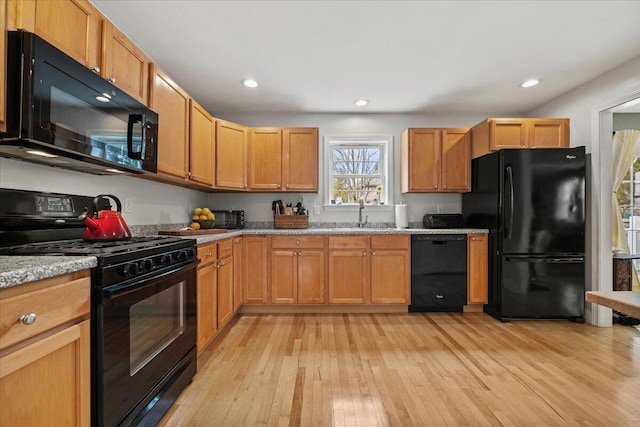 kitchen featuring black appliances, light wood-type flooring, a sink, and recessed lighting