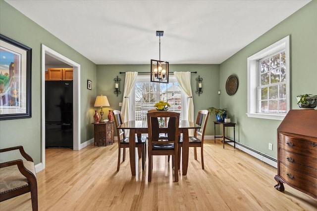 dining room featuring baseboard heating, a chandelier, plenty of natural light, and light wood-type flooring