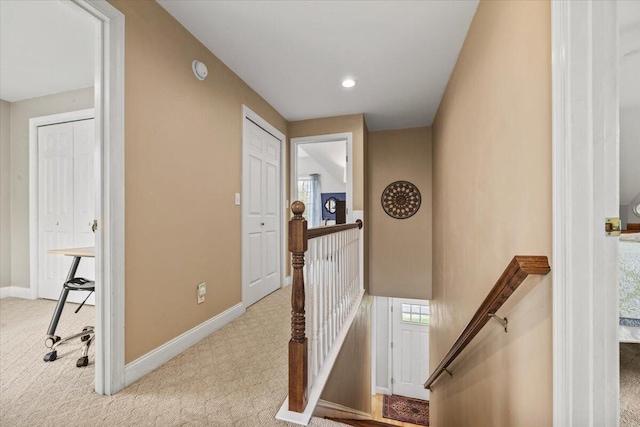 hall with an upstairs landing, carpet floors, and baseboards