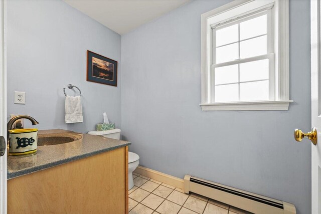 bathroom featuring a baseboard heating unit, toilet, vanity, and baseboards