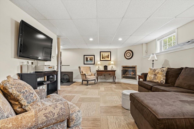 living room featuring a paneled ceiling, baseboards, and recessed lighting