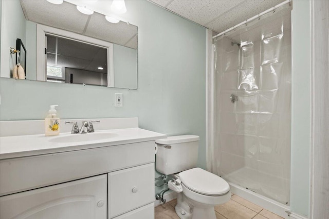 full bathroom featuring a stall shower, toilet, tile patterned flooring, a drop ceiling, and vanity