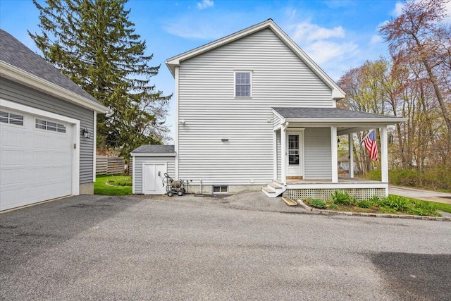 view of property exterior featuring a porch, a garage, and asphalt driveway