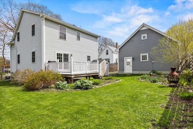 rear view of property with a deck, a lawn, a shed, and an outdoor structure
