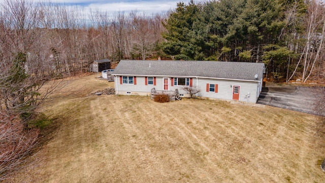 single story home with crawl space, a forest view, a shingled roof, and a front yard