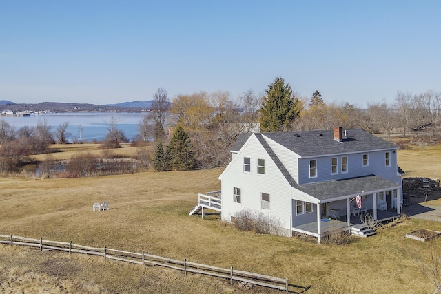 108 N Shore Dr, Owls Head, ME 04854 - rear view of house featuring a deck with water view, a chimney, roof with shingles, and a yard