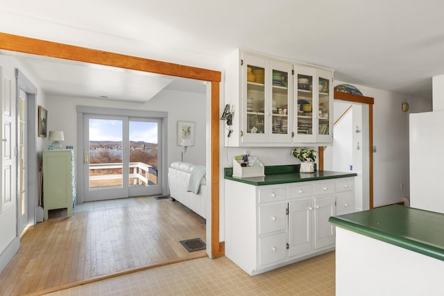 108 N Shore Dr, Owls Head, ME 04854 - kitchen featuring white cabinetry, dark countertops, visible vents, light wood-style flooring, and glass insert cabinets