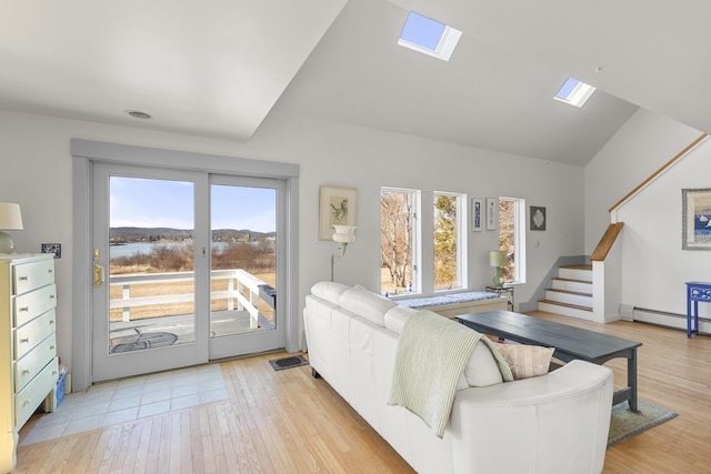 108 N Shore Dr, Owls Head, ME 04854 - living room with a baseboard radiator, light wood-style flooring, vaulted ceiling with skylight, and stairway