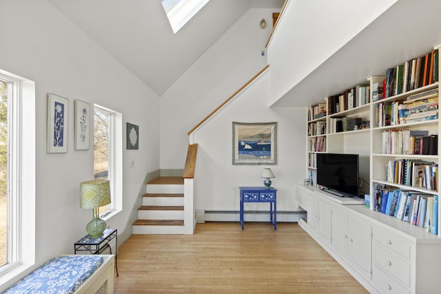 108 N Shore Dr, Owls Head, ME 04854 - living area with stairs, a baseboard heating unit, lofted ceiling with skylight, and light wood finished floors