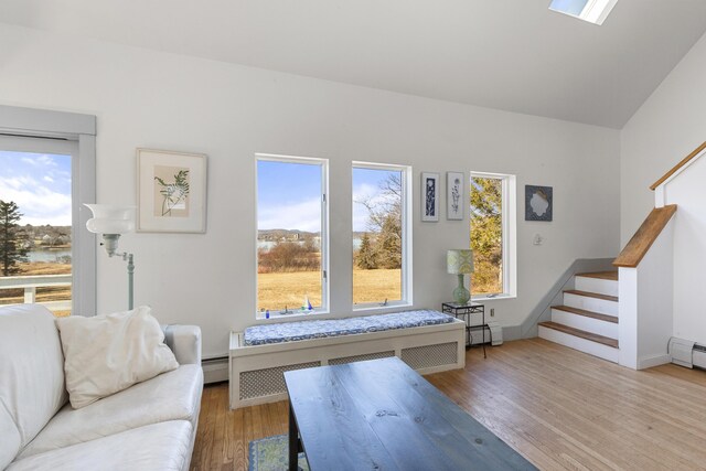 108 N Shore Dr, Owls Head, ME 04854 - interior space featuring vaulted ceiling, a baseboard heating unit, stairs, and wood finished floors