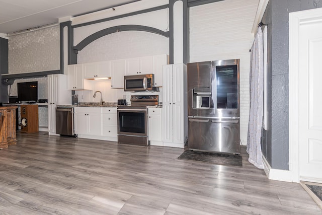 kitchen with wood finished floors, white cabinetry, stainless steel appliances, and a sink