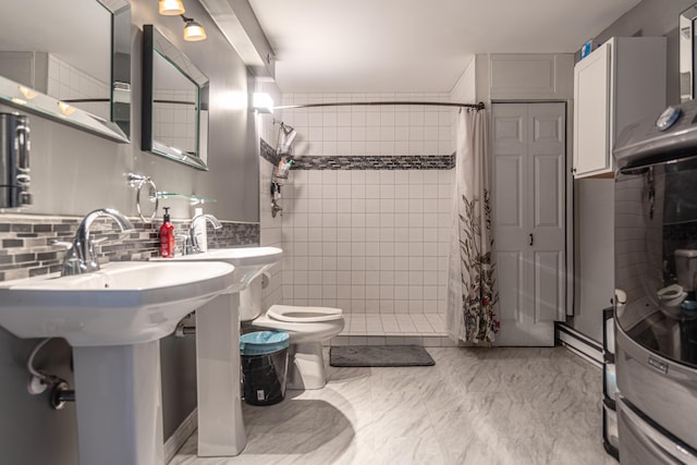 full bathroom featuring decorative backsplash, a tile shower, a sink, and toilet