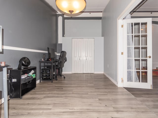 office space with baseboards, wood finished floors, and a towering ceiling