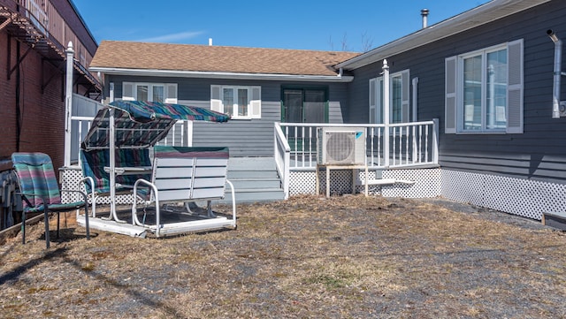 exterior space with roof with shingles, ac unit, and a deck