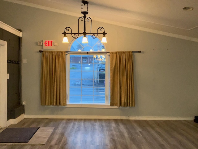 unfurnished dining area with vaulted ceiling, baseboards, a chandelier, and wood finished floors