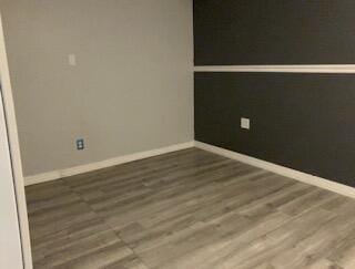 spare room featuring wood finished floors and baseboards