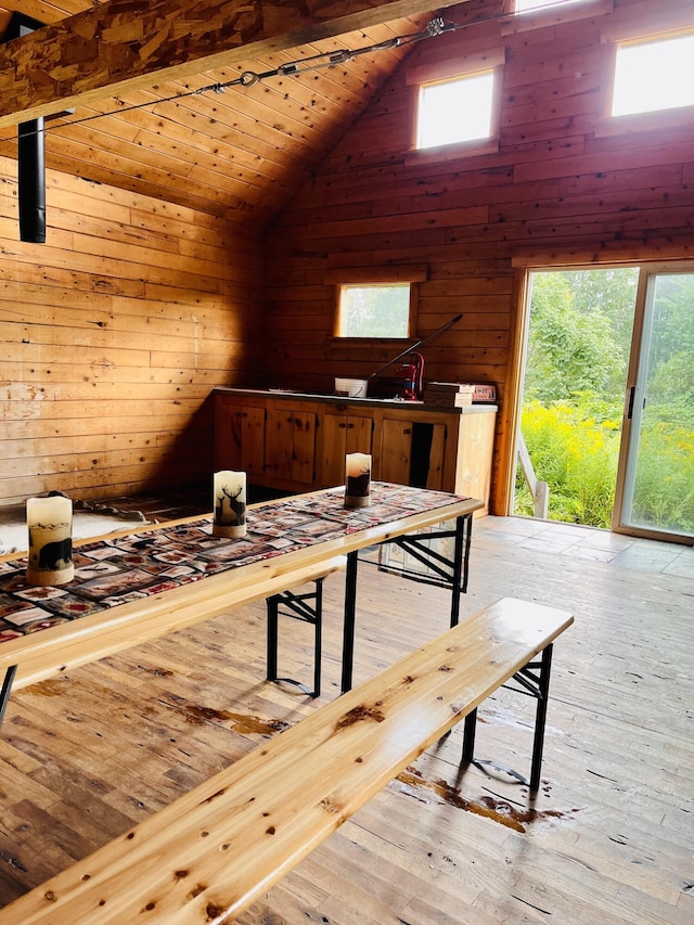 dining area featuring lofted ceiling, hardwood / wood-style flooring, and wood walls