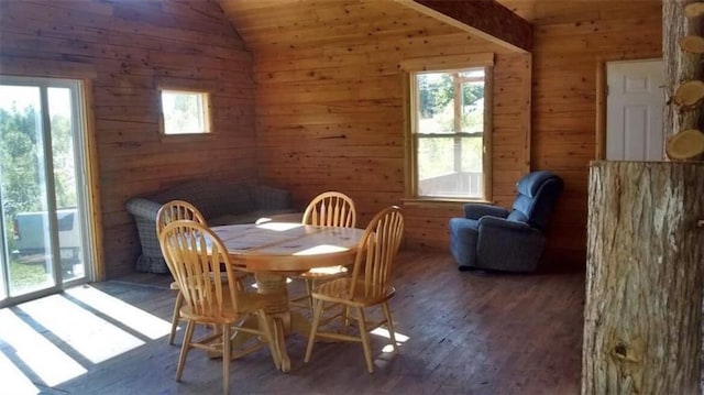 dining room with lofted ceiling, wooden walls, plenty of natural light, and wood finished floors
