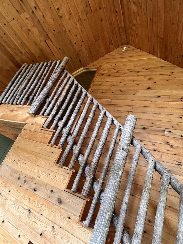 staircase featuring lofted ceiling, wooden walls, and wood ceiling