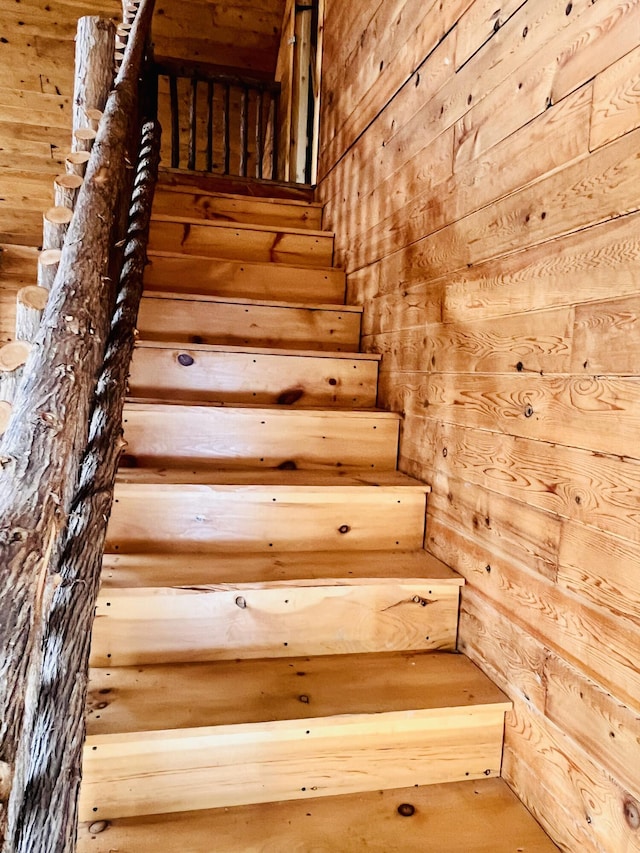 stairway featuring wood walls