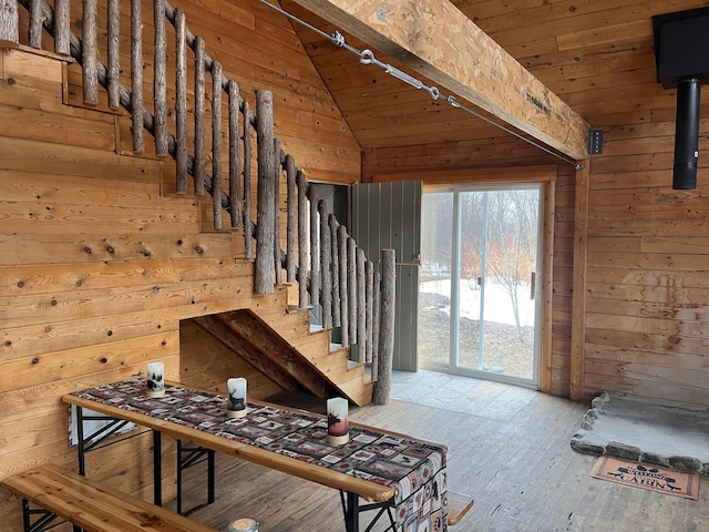 stairs featuring lofted ceiling, wooden walls, wood ceiling, and rail lighting