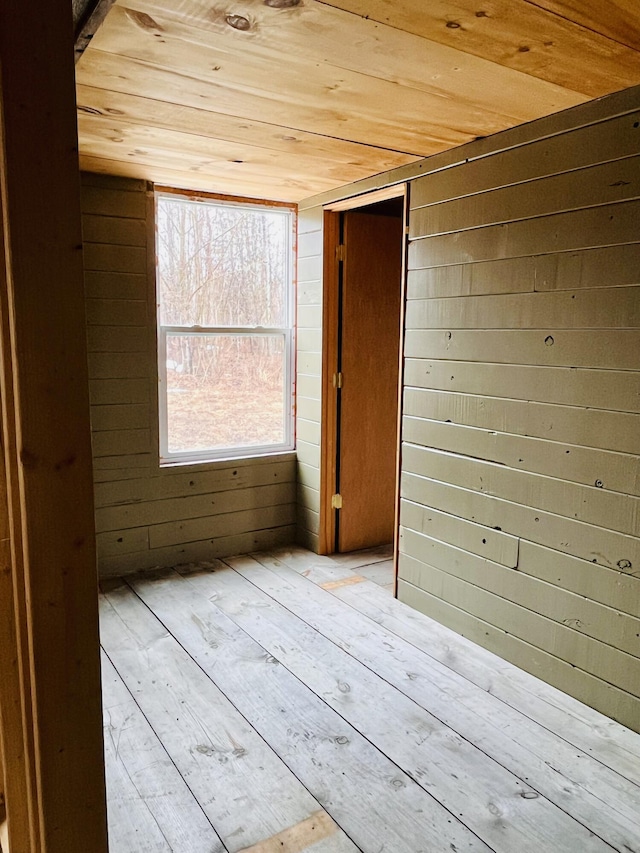 empty room featuring wooden walls, wooden ceiling, and hardwood / wood-style floors