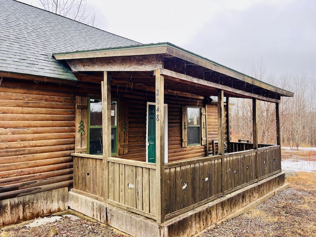 view of property exterior featuring faux log siding and a shingled roof
