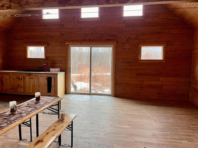 living room with vaulted ceiling, light wood-style flooring, wood ceiling, and wood walls