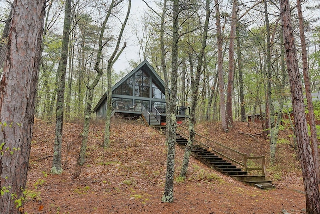 view of front of property with a forest view, a deck, and stairs