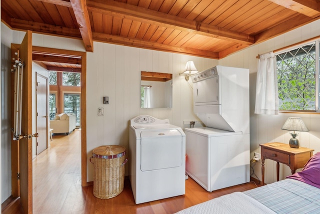laundry room featuring light wood-type flooring, laundry area, stacked washer / drying machine, and wood ceiling