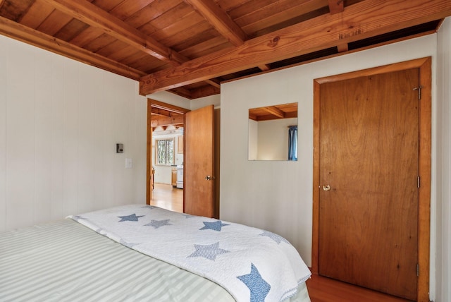 bedroom with beam ceiling, wooden walls, wood finished floors, and wood ceiling