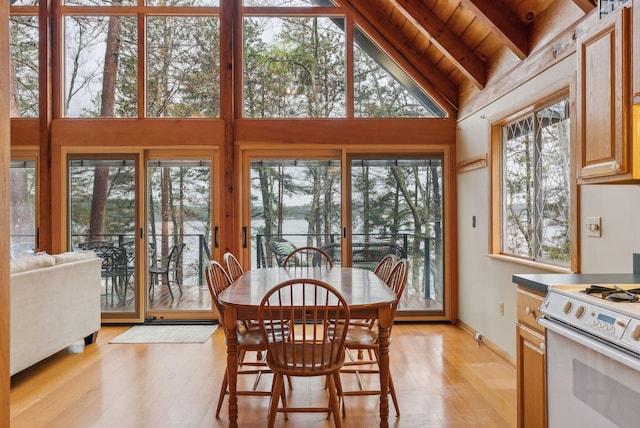 dining space featuring light wood finished floors, wood ceiling, beamed ceiling, and high vaulted ceiling