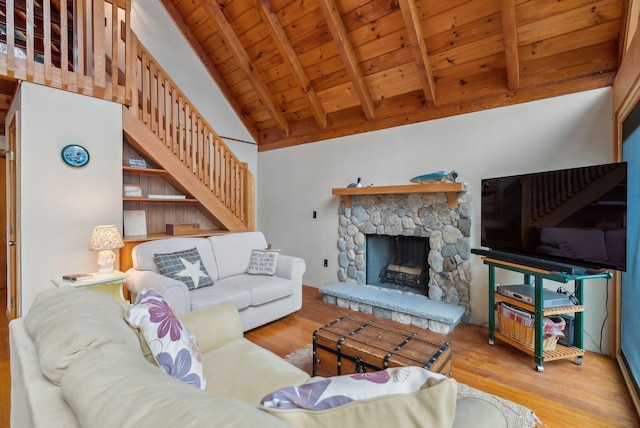 living area featuring wood ceiling, wood finished floors, vaulted ceiling with beams, stairway, and a stone fireplace