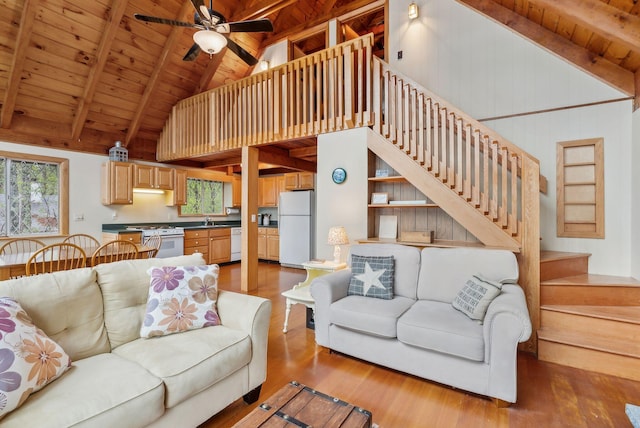 living room featuring wood ceiling, wood finished floors, a ceiling fan, beam ceiling, and stairs