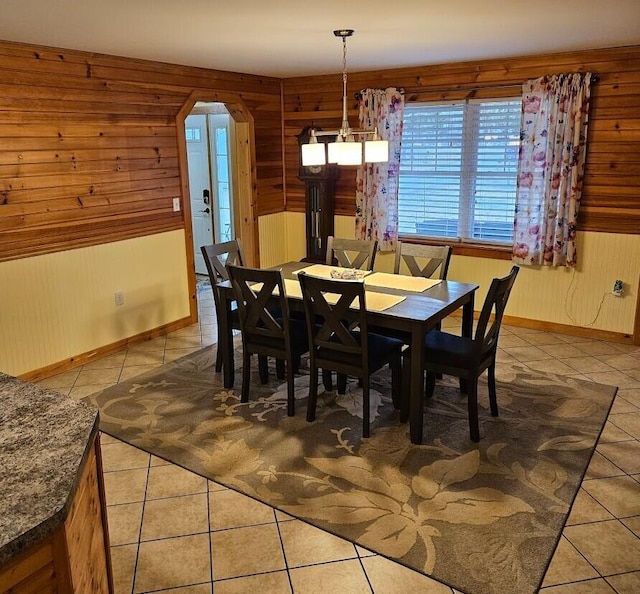 277 Grant Rd, Saint Albans, ME 04971 - dining room with light tile patterned floors, arched walkways, wooden walls, baseboards, and a notable chandelier