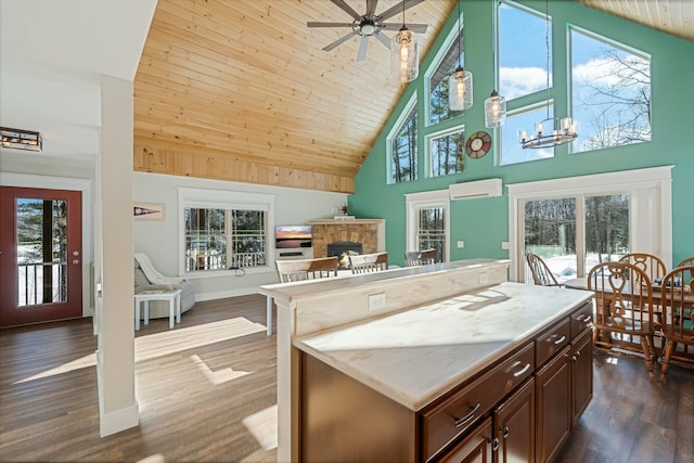 kitchen with open floor plan, dark wood-style flooring, a wall unit AC, and a stone fireplace