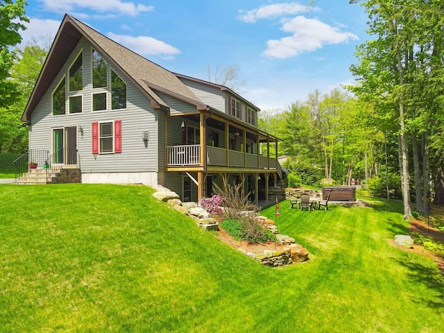 rear view of property with a hot tub and a yard