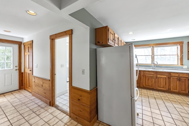 kitchen with a sink, light countertops, freestanding refrigerator, recessed lighting, and light tile patterned flooring