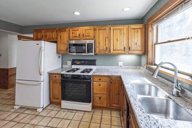 kitchen featuring freestanding refrigerator, recessed lighting, stainless steel microwave, a sink, and range with gas cooktop