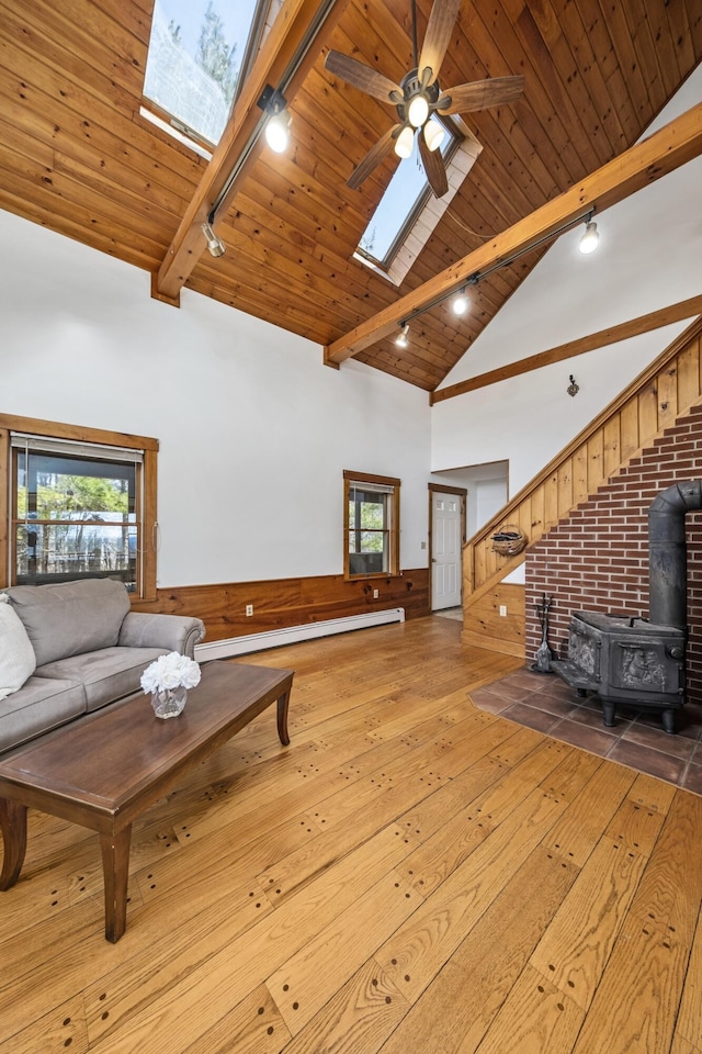 unfurnished living room with a wood stove, wood ceiling, beam ceiling, wood-type flooring, and a skylight