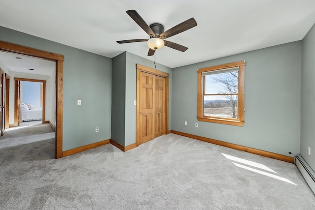 unfurnished bedroom with a closet, carpet, baseboard heating, and baseboards