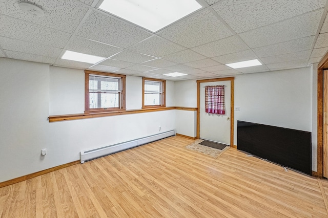 interior space featuring light wood-style flooring, a paneled ceiling, a baseboard heating unit, and baseboards