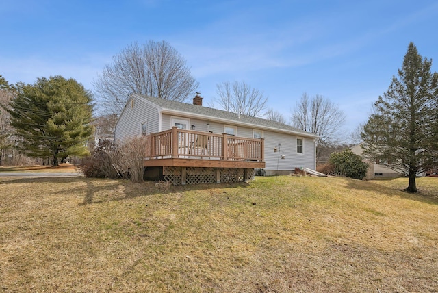 back of house featuring a yard, a deck, and a chimney