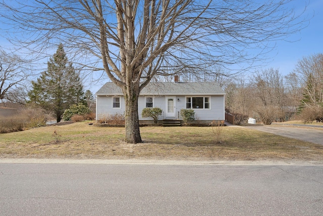 view of front of house with driveway, a chimney, and a front lawn