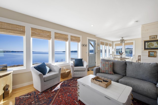living room featuring baseboards, wood finished floors, a water view, and ceiling fan