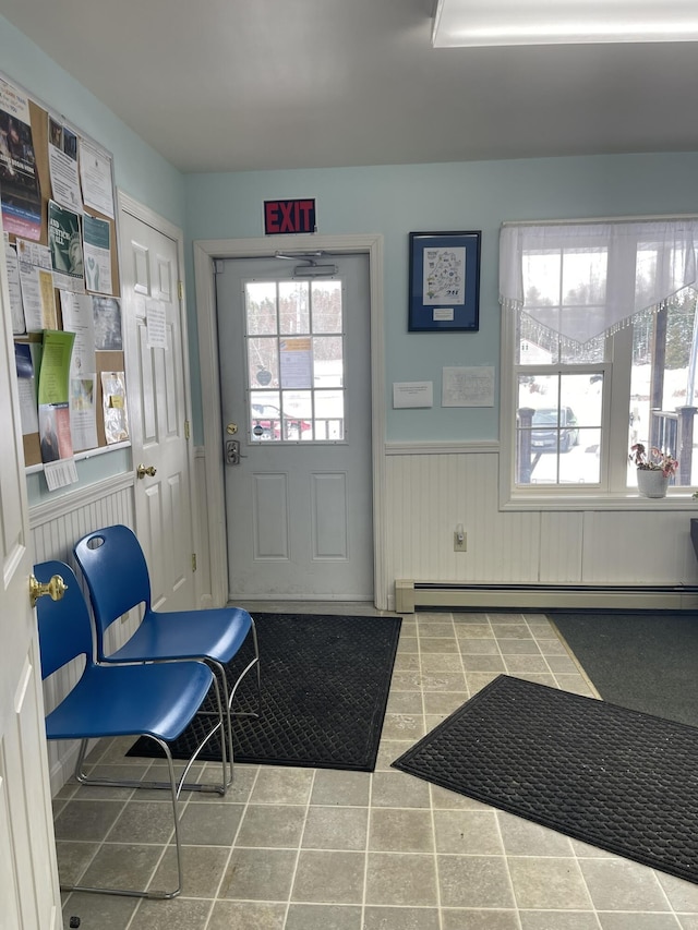 doorway to outside with baseboard heating and wainscoting